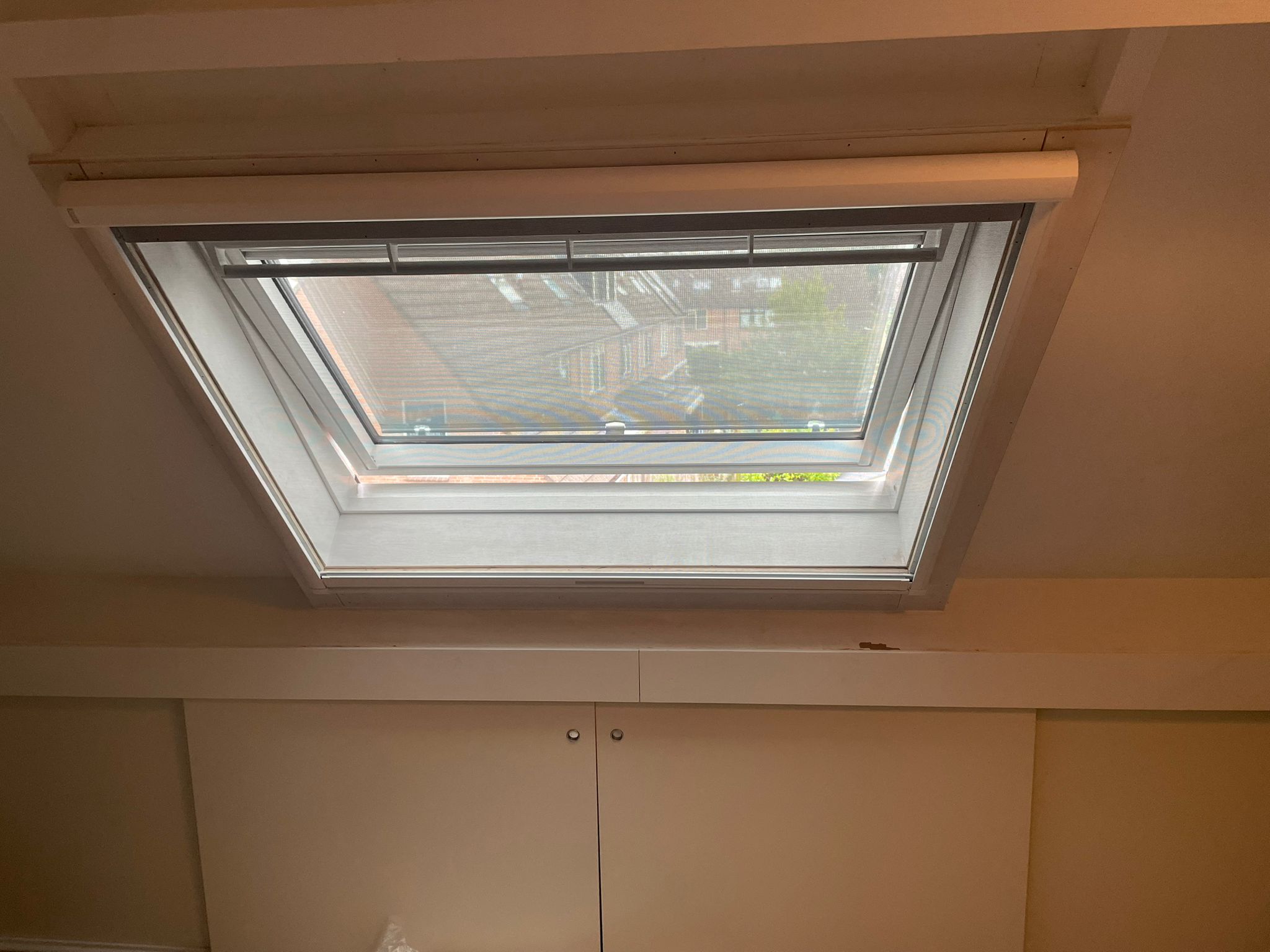 Afgewerkte zolder met een dakraam in het schuine plafond en kastjes onder de schuinte